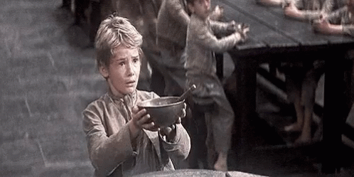 A Young Boy Is Holding A Bowl With A Spoon In It In Front Of A Group Of Children . GIF