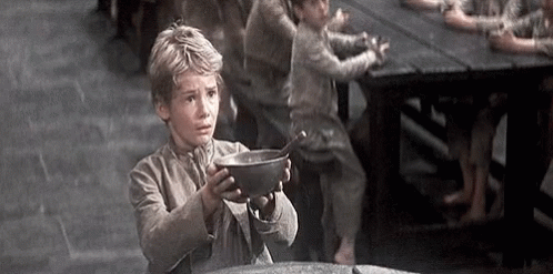 A Young Boy Is Holding A Bowl With A Spoon In It . GIF