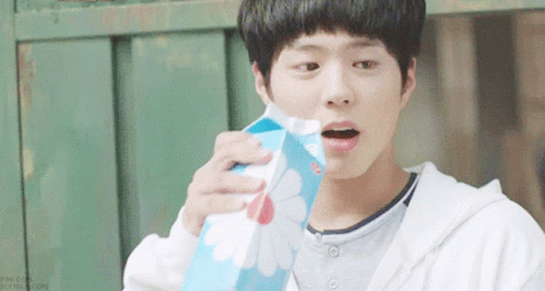 A Young Boy Is Holding A Carton Of Milk With A Flower Design On It GIF