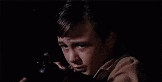 A Young Boy Is Holding A Gun In His Hand And Crying In The Dark . GIF