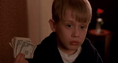 A Young Boy Is Holding A Stack Of Dollar Bills In His Hand . GIF