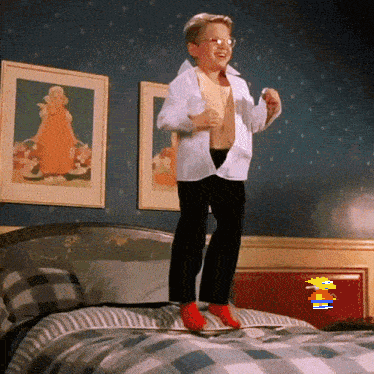 A Young Boy Is Jumping On Top Of A Bed With A Cartoon Character In The Background GIF