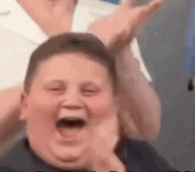 A Young Boy Is Laughing With His Mouth Open While Being Held By A Person . GIF