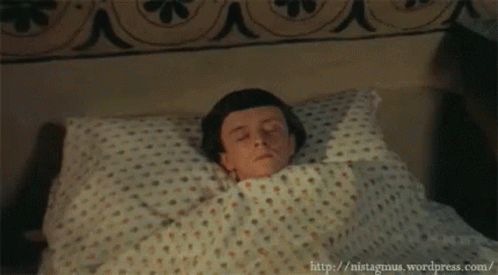 A Young Boy Is Laying In Bed With His Eyes Closed GIF