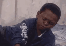 A Young Boy Is Laying On A Bed With His Eyes Closed And His Mouth Open . GIF