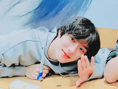 A Young Boy Is Laying On A Table With A Pen In His Hand And A Sticker That Says ' A ' On It GIF
