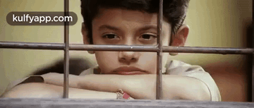A Young Boy Is Looking Out Of A Window With His Head Resting On A Railing . GIF
