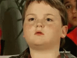 A Young Boy Is Making A Funny Face In Front Of A Sign That Says " Adult Swim " GIF
