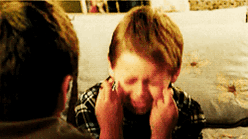A Young Boy Is Making A Funny Face While Sitting On A Couch With A Man . GIF