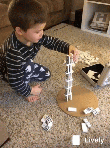 A Young Boy Is Playing A Game Of Dominoes On The Floor With The Word Lively In The Corner GIF
