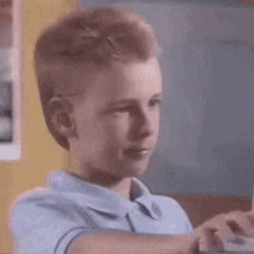 A Young Boy Is Playing A Video Game On A Computer While Looking At The Screen . GIF