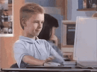 A Young Boy Is Sitting At A Desk In Front Of A Laptop Computer GIF