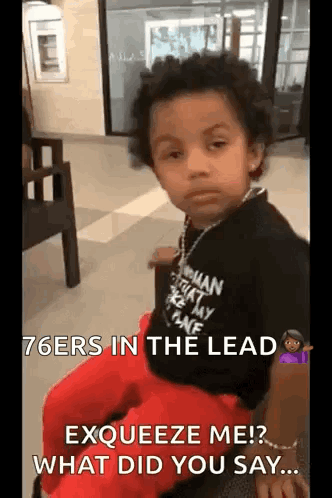 A Young Boy Is Sitting In A Chair In A Waiting Room With A Necklace Around His Neck . GIF