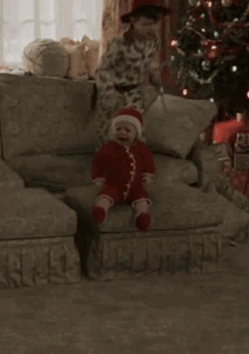 A Young Boy Is Sitting On A Couch Next To A Stuffed Monkey . GIF