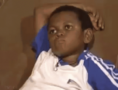 A Young Boy Is Sitting On A Couch With His Hands On His Head And Making A Funny Face . GIF