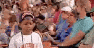 A Young Boy Is Standing In Front Of A Crowd Of People . GIF