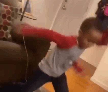 A Young Boy Is Standing Next To A Couch In A Living Room And Dancing . GIF