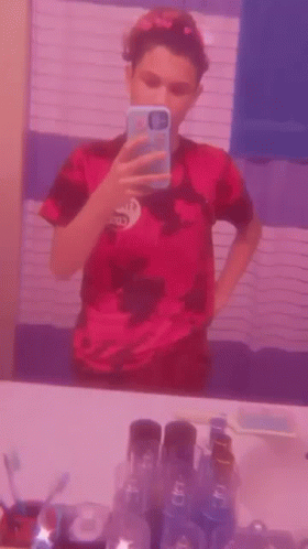 A Young Boy Is Taking A Selfie In Front Of A Mirror . GIF