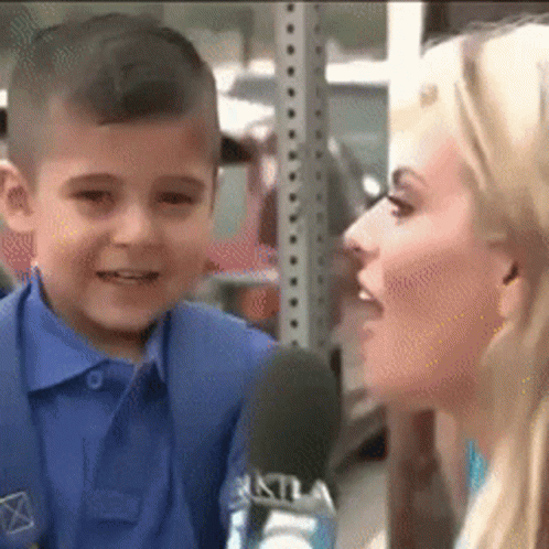 A Young Boy Is Talking Into A Microphone While A Woman Looks On . GIF