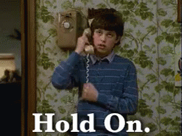 A Young Boy Is Talking On A Telephone With The Words Hold On Written On The Bottom GIF