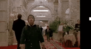 A Young Boy Is Walking Down A Hallway In A Hotel . GIF