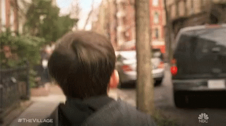 A Young Boy Is Walking Down A Street With A Van Behind Him . GIF