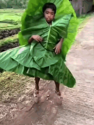 A Young Boy Is Wearing A Green Leaf Dress And High Heels GIF