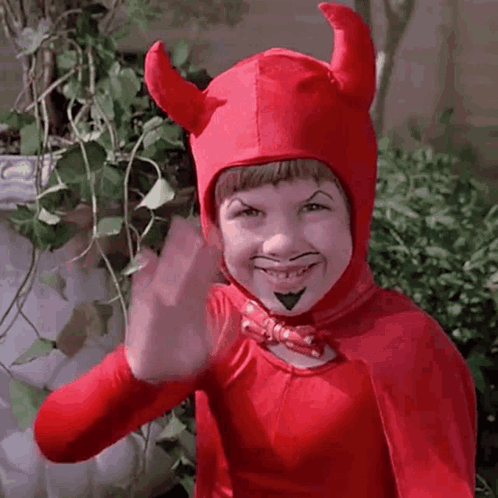 A Young Boy Is Wearing A Red Devil Costume And Waving . GIF