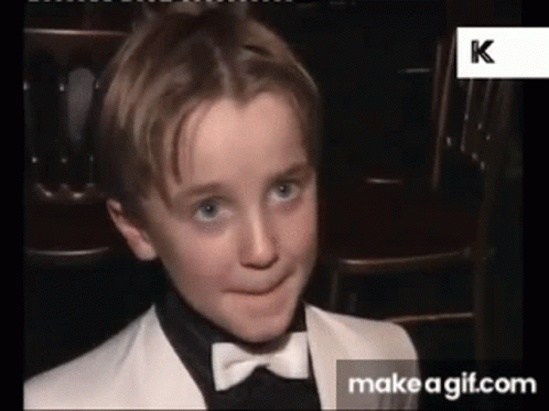 A Young Boy Is Wearing A Tuxedo And Bow Tie And Making A Funny Face . GIF