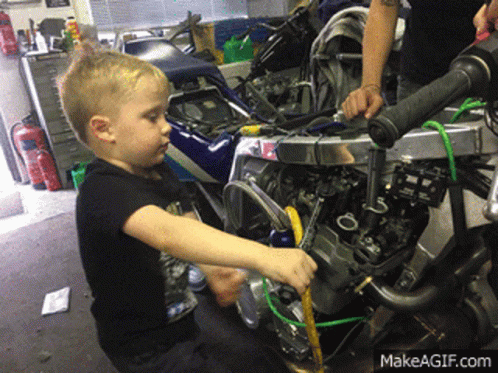A Young Boy Is Working On A Motorcycle With A Makeagif.com Watermark GIF