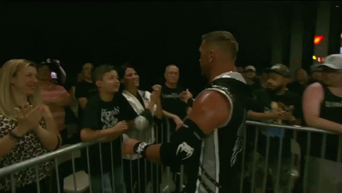 A Young Boy Kisses A Man On The Cheek In Front Of A Crowd GIF