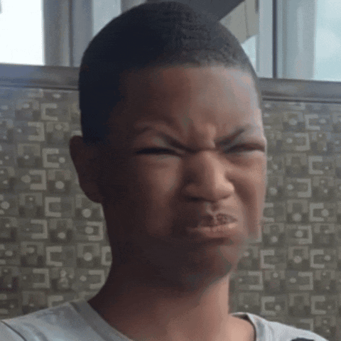 A Young Boy Making A Funny Face In Front Of A Wall With A Pattern Of Letters GIF