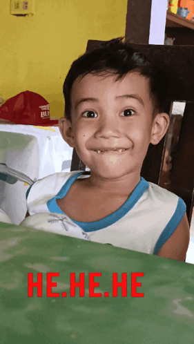 A Young Boy Making A Funny Face With The Words He.he.he. In Red Behind Him GIF