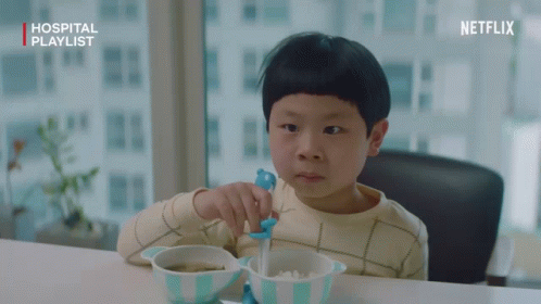 A Young Boy Sitting At A Table With A Bowl Of Food And A Netflix Logo GIF
