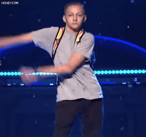 A Young Boy Wearing A Backpack Is Dancing On A Stage . GIF