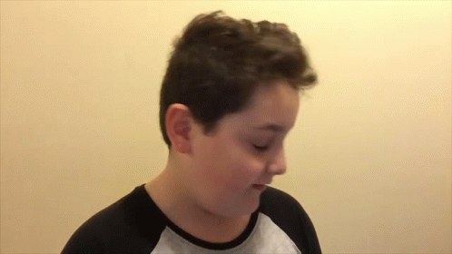 A Young Boy Wearing A Black And Gray Shirt Is Making A Funny Face GIF