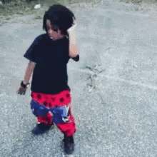A Young Boy Wearing A Black Shirt And Red And Blue Pants GIF