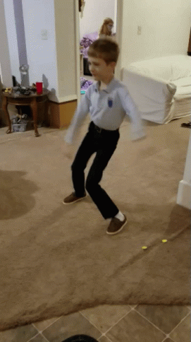 A Young Boy Wearing A Blue Shirt And Black Pants Is Jumping In The Air GIF