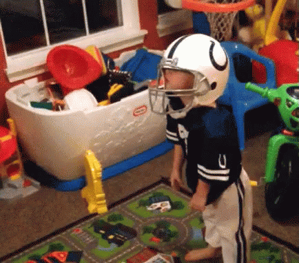 A Young Boy Wearing A Football Helmet And A Little Tikes Toy Chest GIF