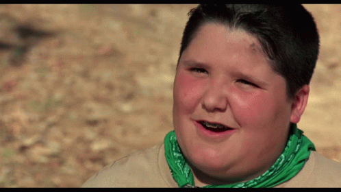 A Young Boy Wearing A Green Bandana And Braces Smiles GIF