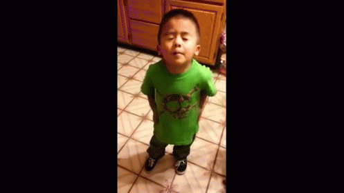 A Young Boy Wearing A Green Shirt Is Standing On A Tiled Floor . GIF