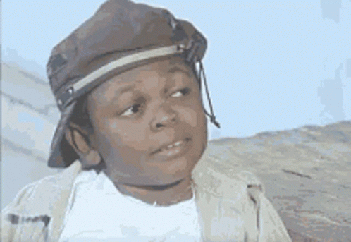 A Young Boy Wearing A Hat And A Jacket Is Making A Face . GIF