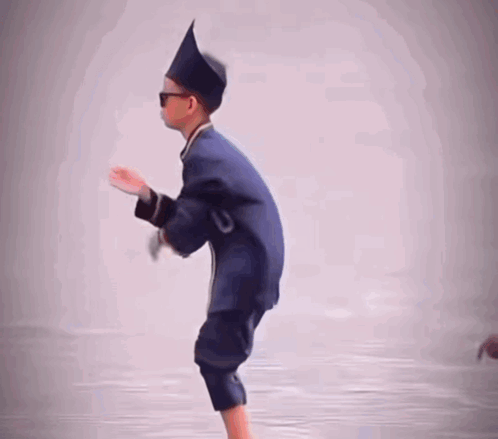 a young boy wearing a hat and sunglasses is standing on one leg
