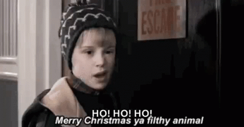 A Young Boy Wearing A Hat Is Standing In Front Of A Door And Saying Merry Christmas Ya Filthy Animal . GIF