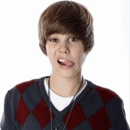 A Young Boy Wearing A Plaid Sweater Is Sticking Out His Tongue . GIF