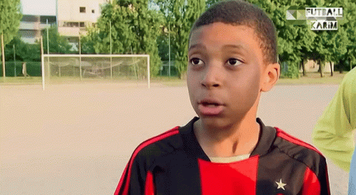A Young Boy Wearing A Red And Black Jersey With A Star On The Front GIF
