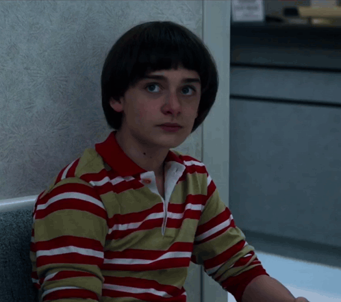 A Young Boy Wearing A Red And White Striped Shirt Looks At The Camera GIF