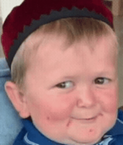 a young boy wearing a red hat and a blue shirt is smiling