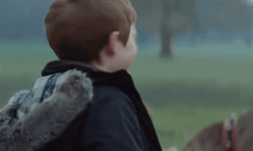 A Young Boy Wearing A Sweater And A Jacket Is Laughing GIF