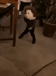 a young boy wearing a white mask is standing next to a potted plant .